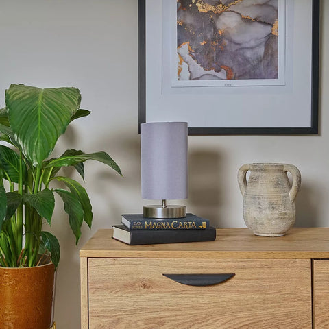 Adjustable brightness chrome lamp placed beside cozy sofa – UK reading nook.

