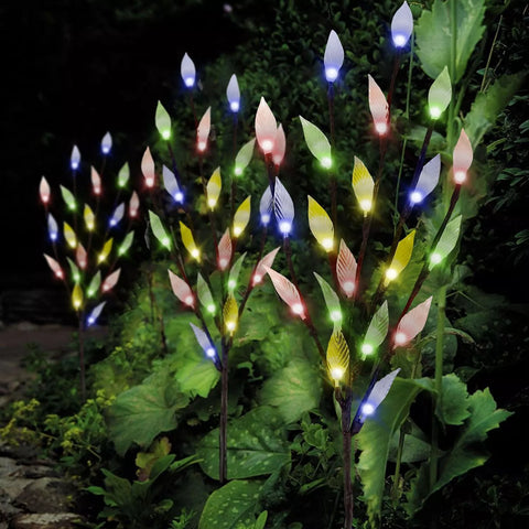 Decorative tree light illuminating flower bed

