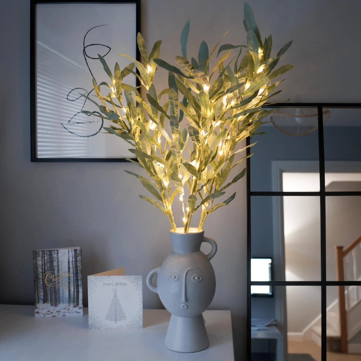 Decorative plant with lights in a vase on a table, with a blurred background
