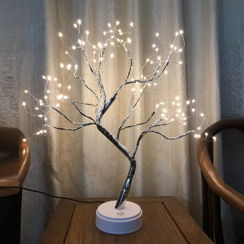 Battery-powered LED tree lamp glowing warmly on a tabletop

